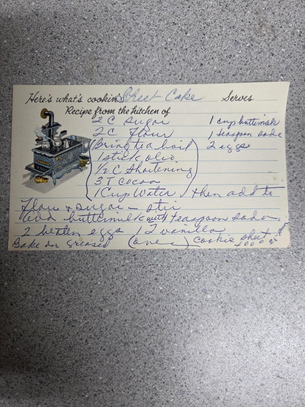 A 'Here's what's cookin&rsquo;' card with a wood-stove illustration — sheet cake, in two different hands